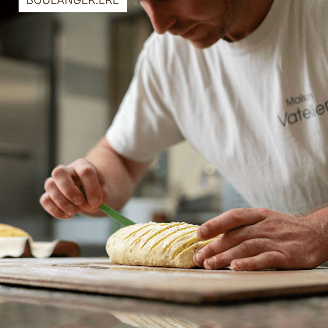 Boulanger façonnant un pâton de pain sur un plan de travail en bois.