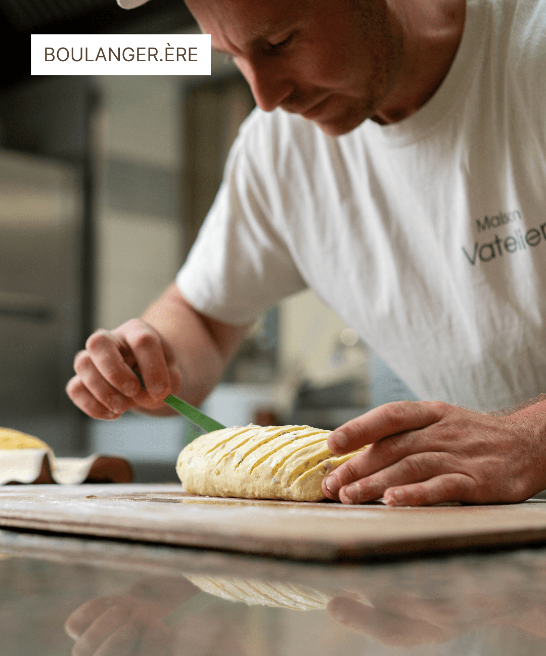 Boulanger façonnant un pâton de pain sur un plan de travail en bois.