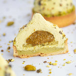 Coupe d'un gâteau Pure Pistache de Maison Vatelier avec insert praliné et mousse légère.