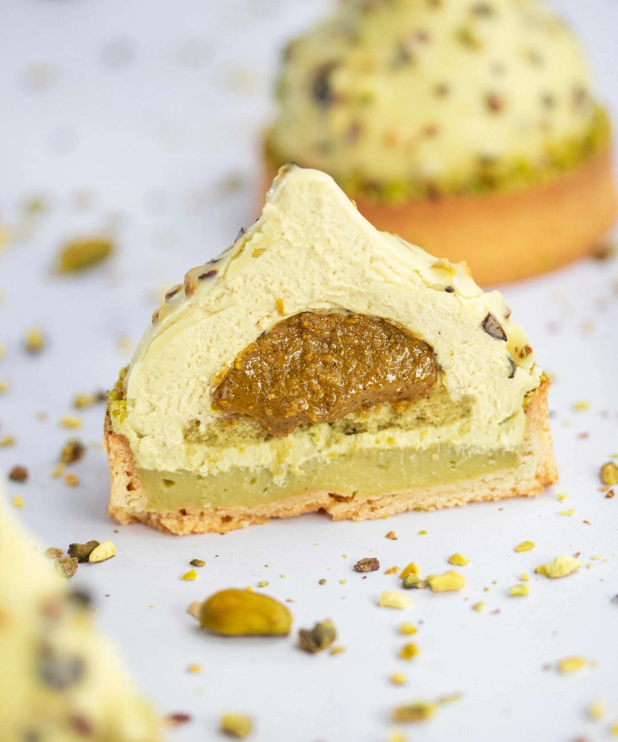 Coupe d'un gâteau Pure Pistache de Maison Vatelier avec insert praliné et mousse légère.