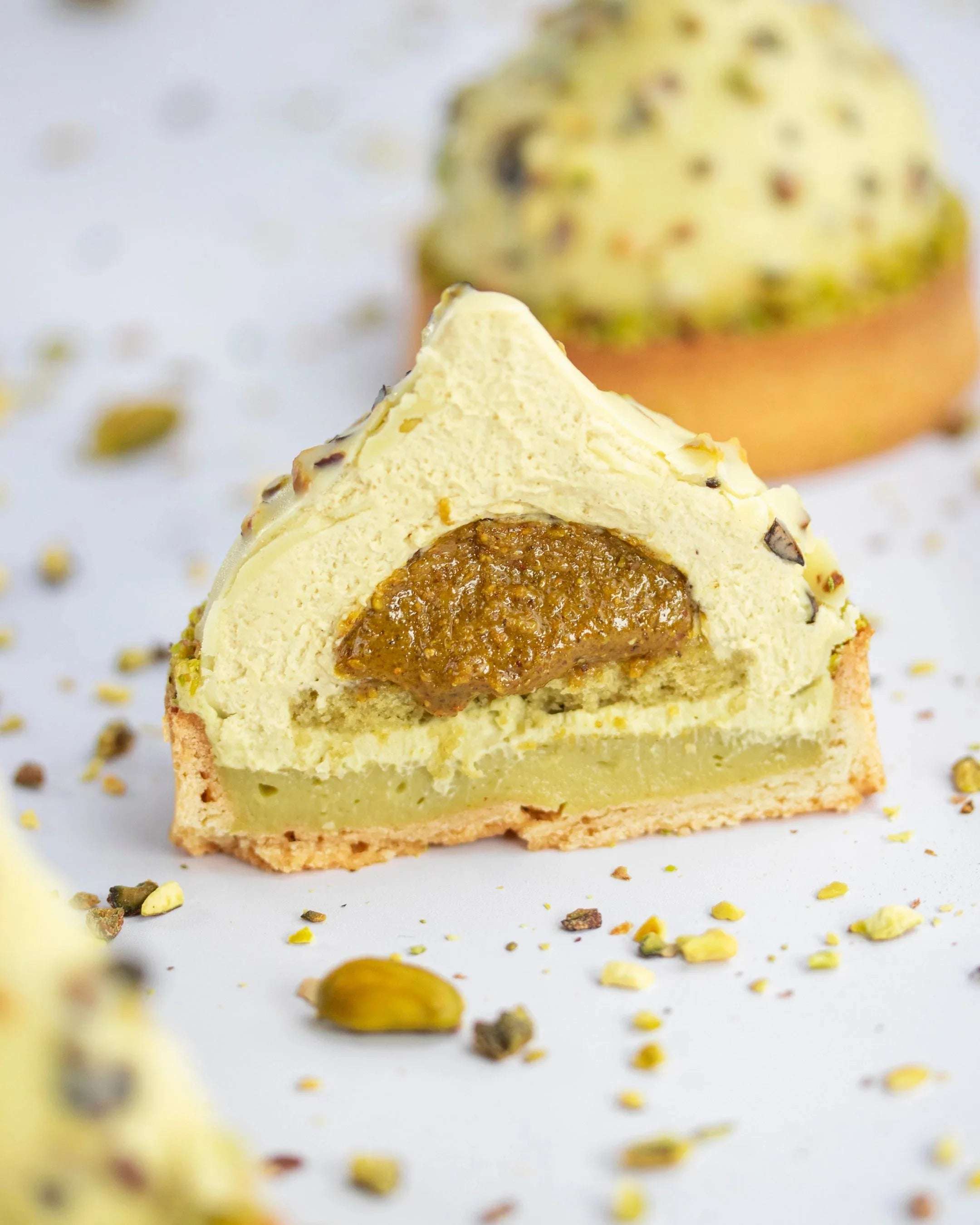 Coupe d'un gâteau Pure Pistache de Maison Vatelier avec insert praliné et mousse légère.