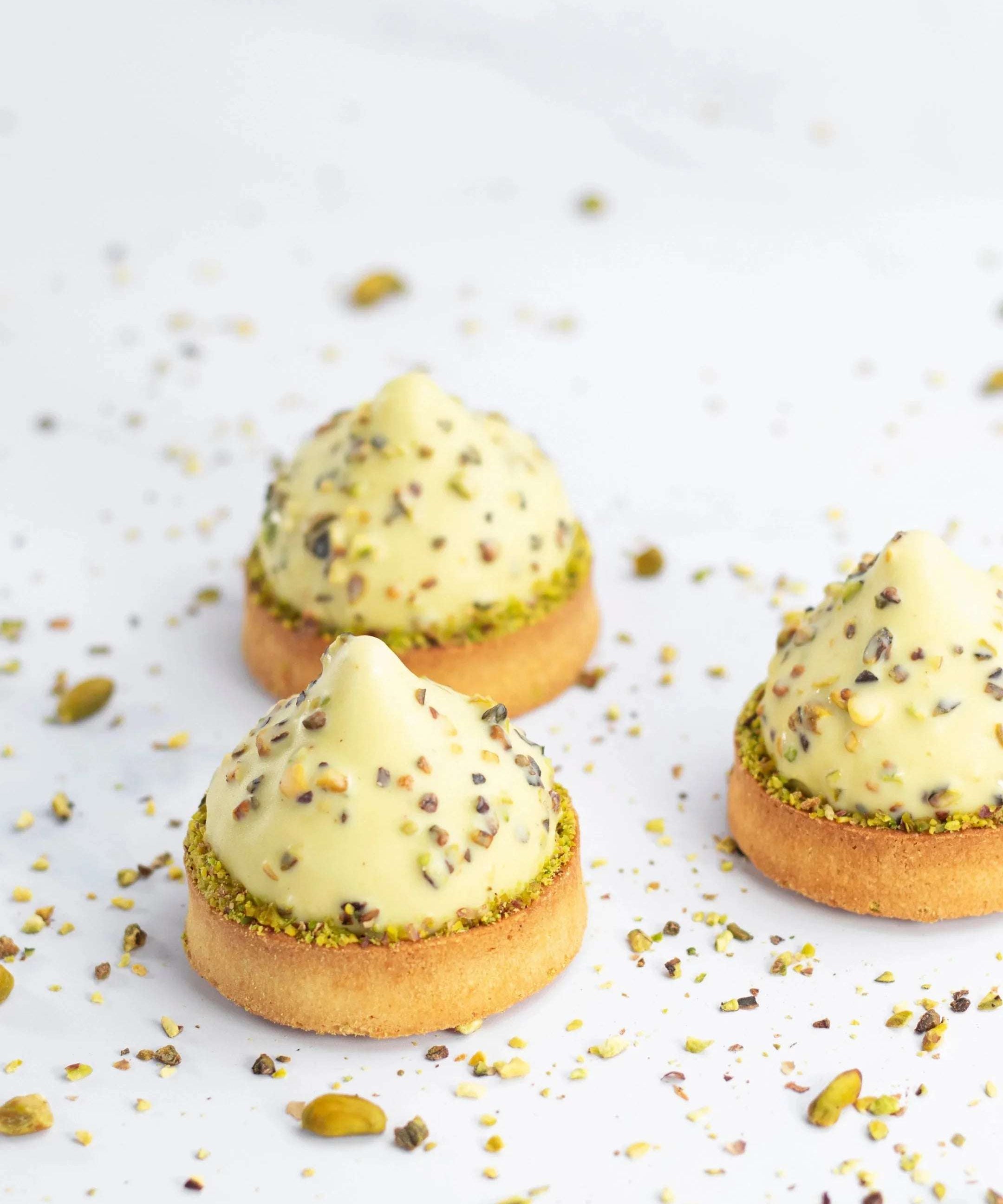 Trois mignardises Pure Pistache de Maison Vatelier avec crème et éclats de pistaches.