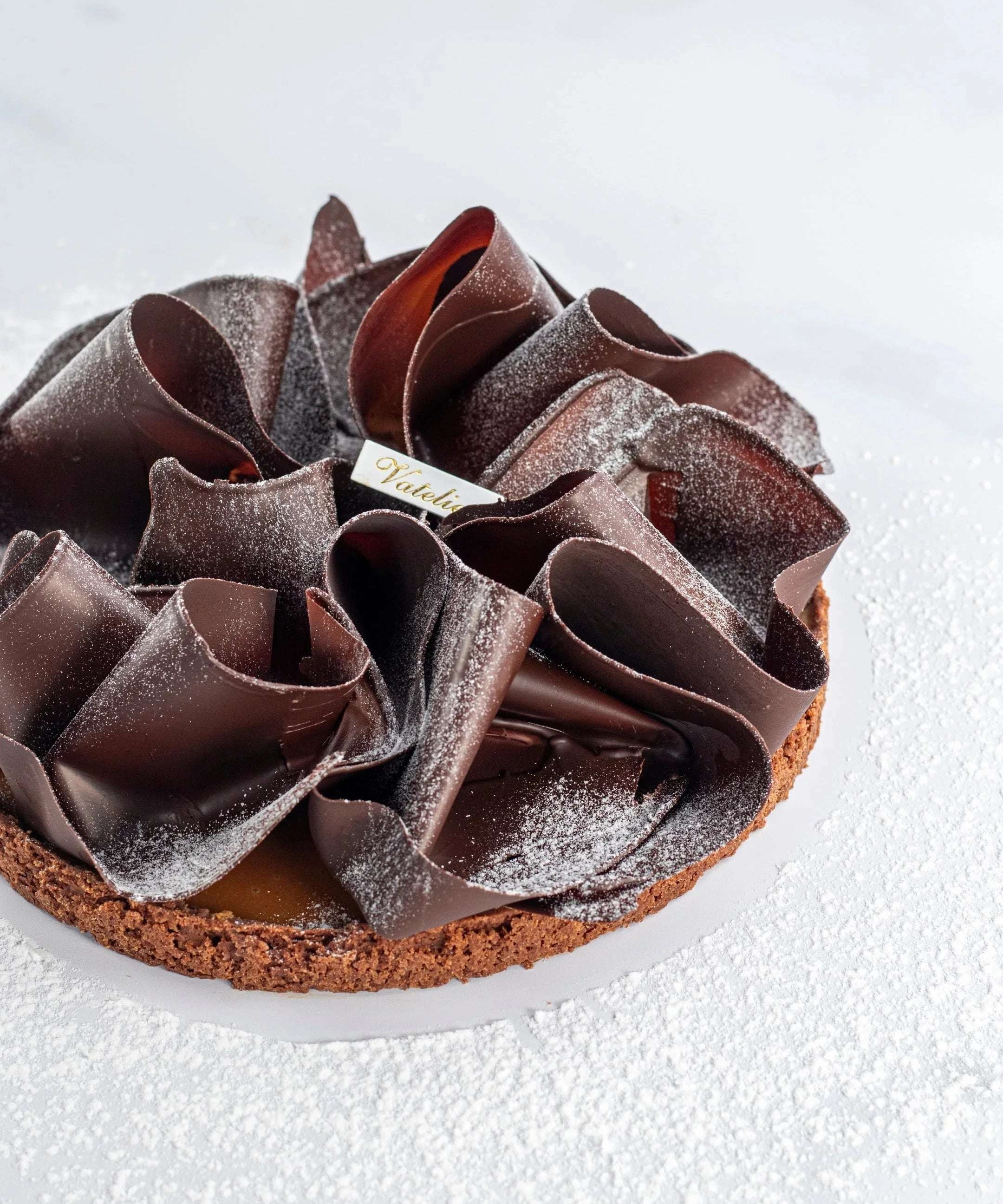 Tarte au caramel beurre salé Maison Vatelier avec copeaux de chocolat et sucre glace.