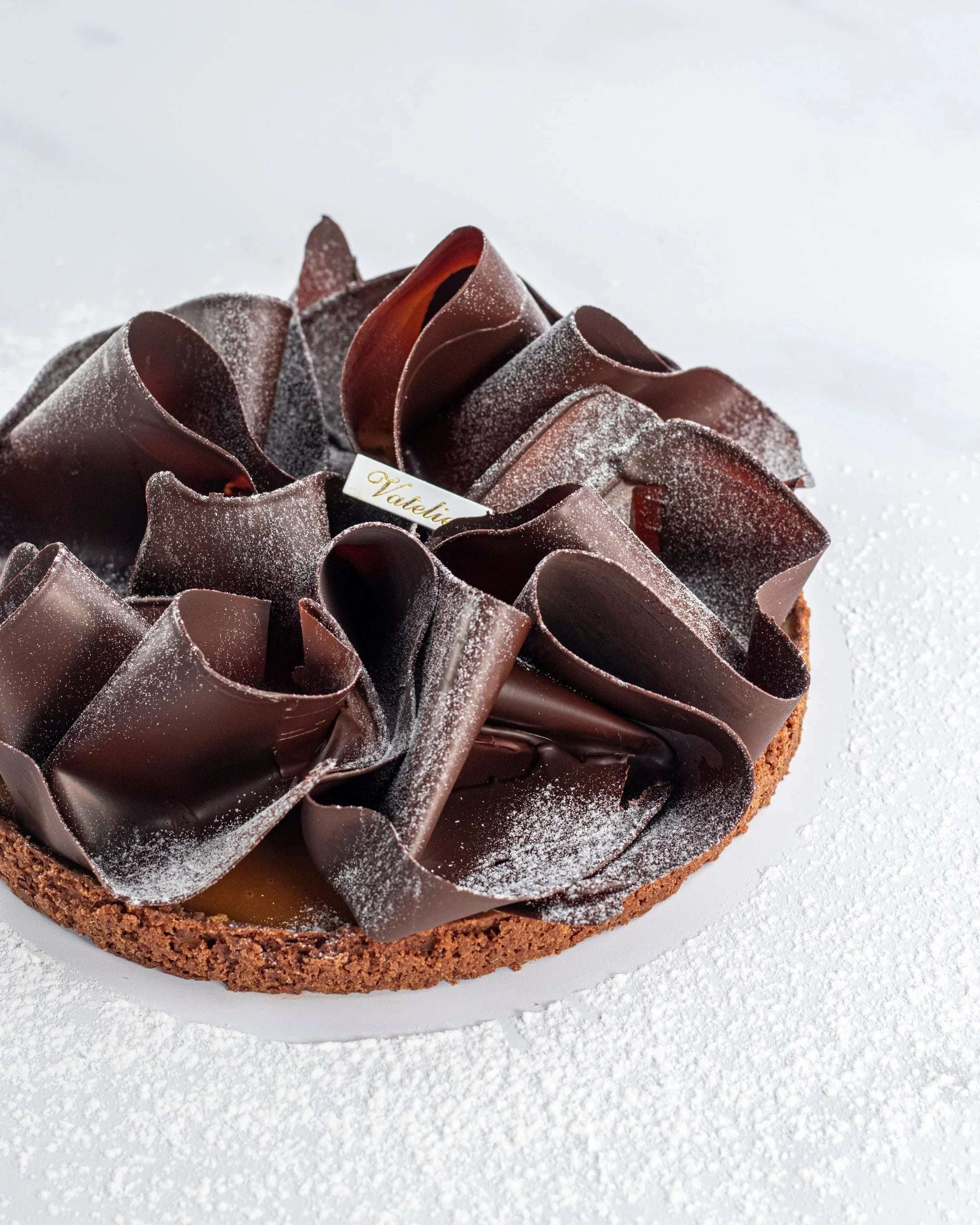 Tarte au caramel beurre salé Maison Vatelier avec copeaux de chocolat et sucre glace.
