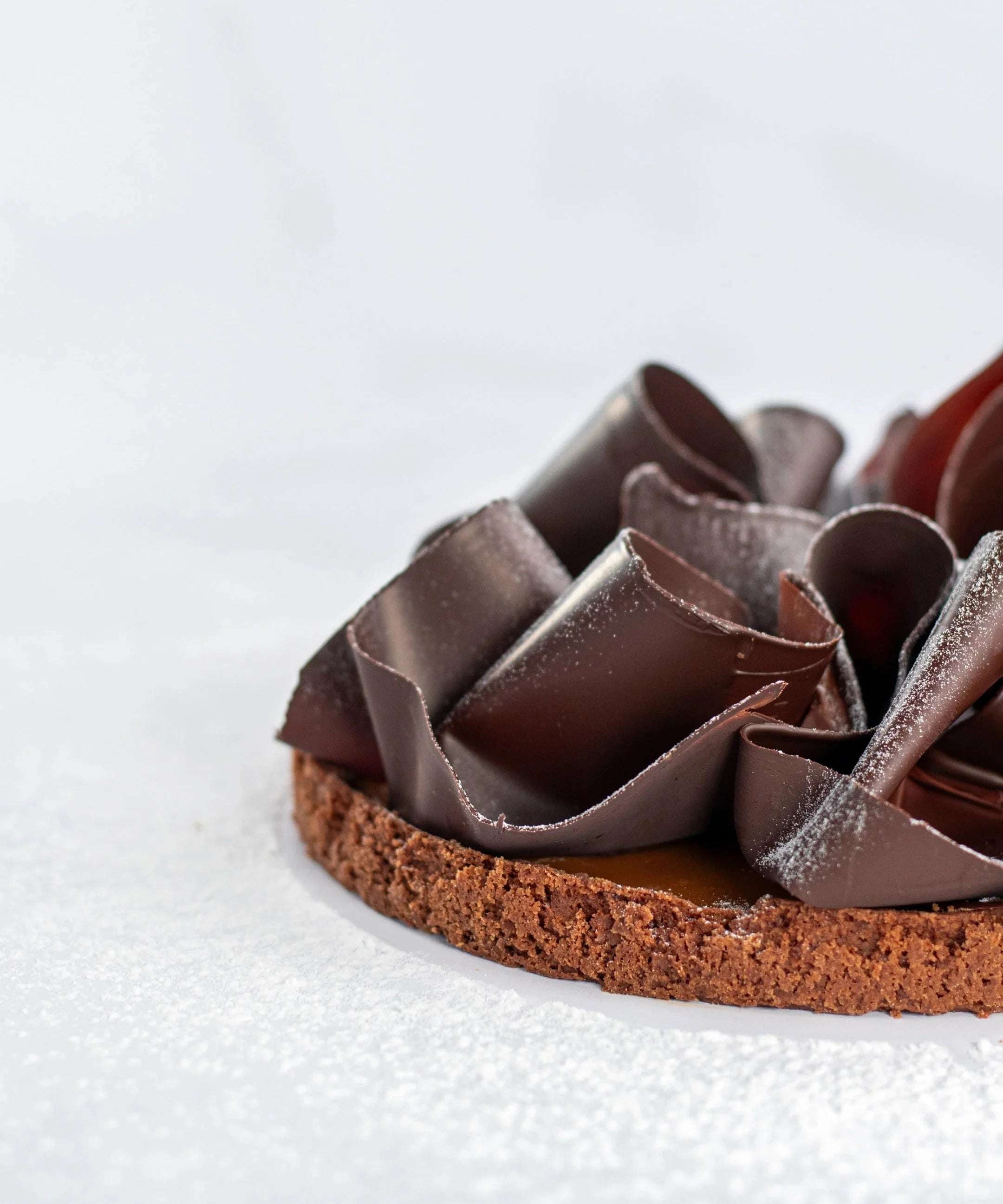 Tarte au caramel beurre salé Maison Vatelier avec copeaux de chocolat et sucre glace.