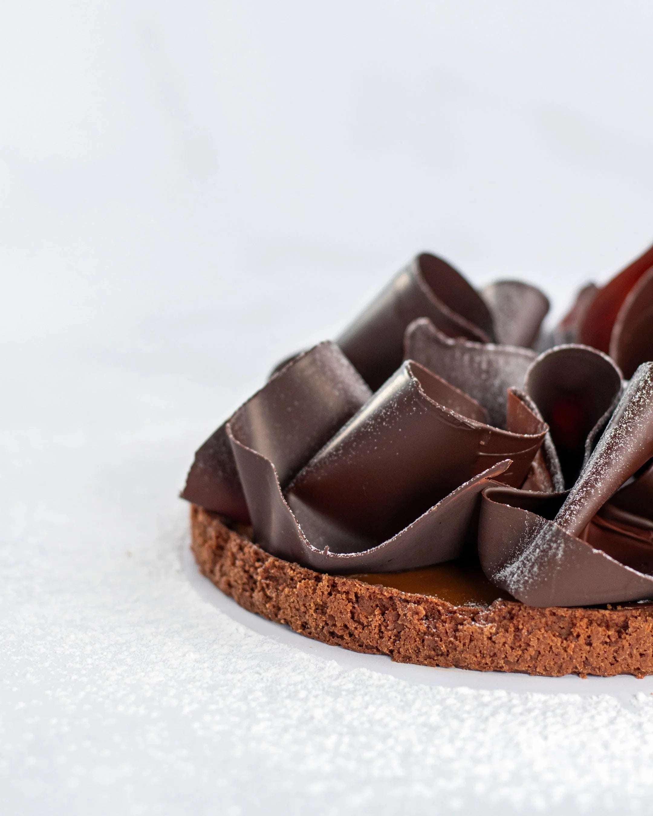 Tarte au caramel beurre salé Maison Vatelier avec copeaux de chocolat et sucre glace.