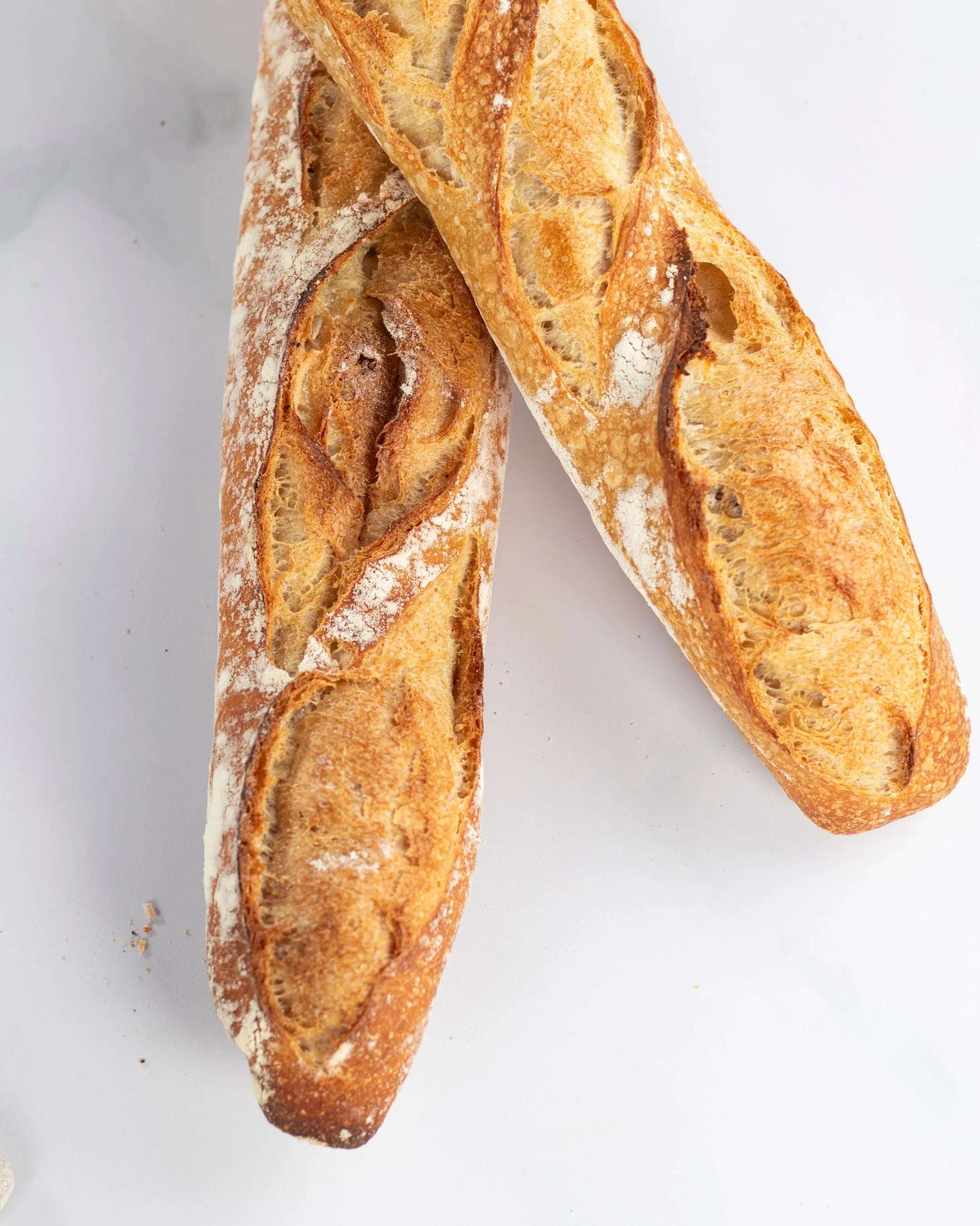 Deux baguettes de tradition Maison Vatelier avec une croûte dorée et croustillante.