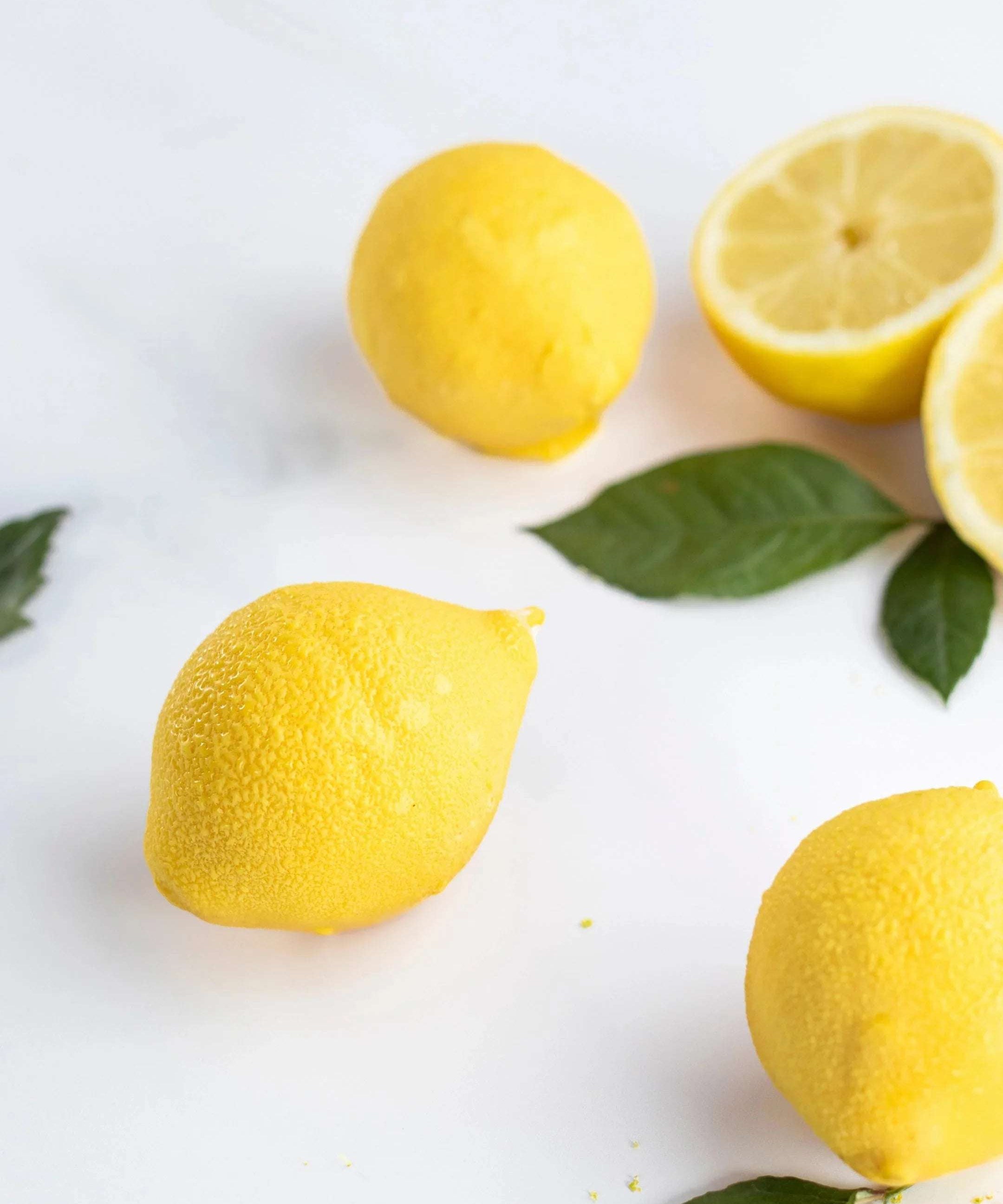 Citrons jaunes frais entiers et coupés avec des feuilles vertes sur fond blanc