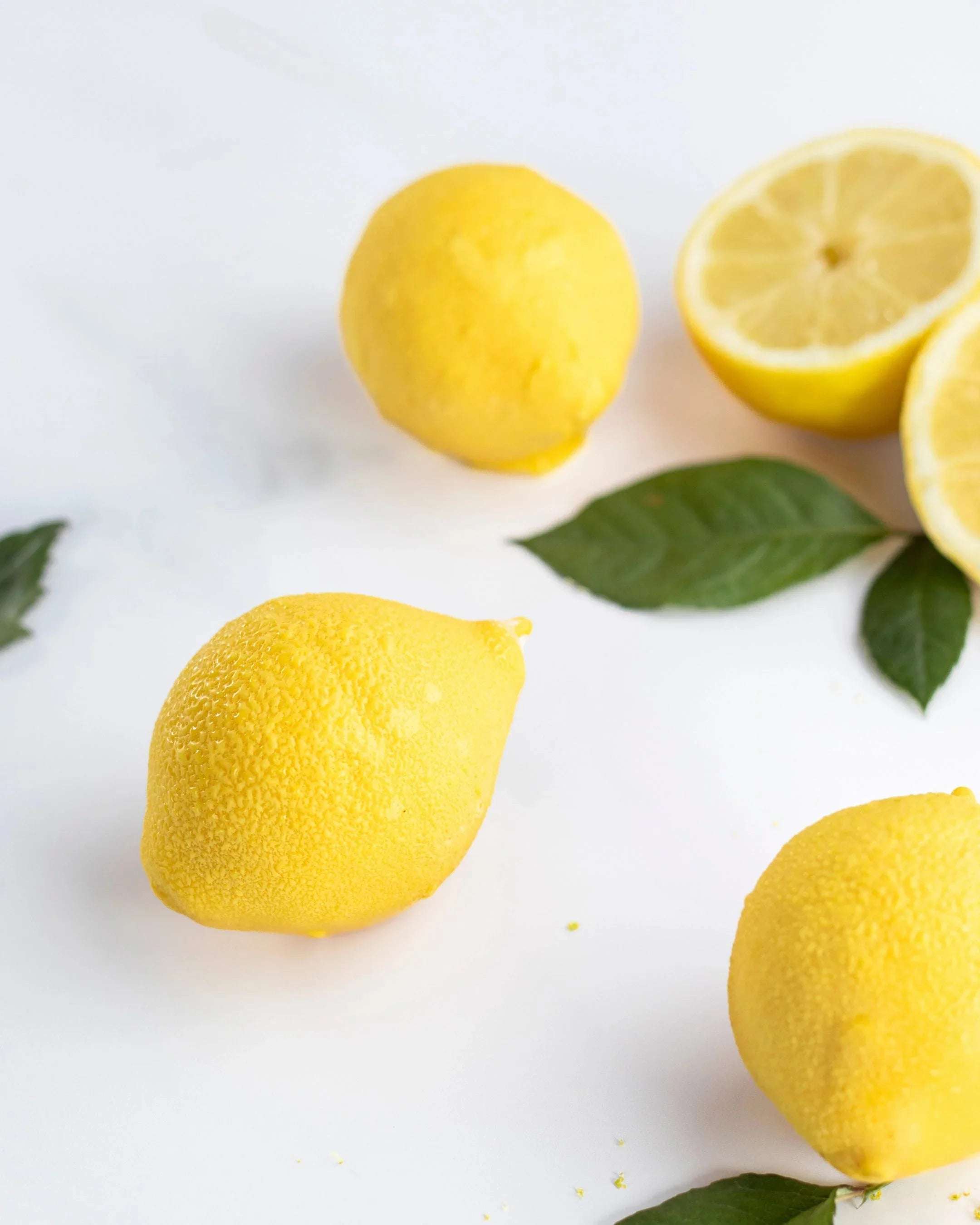 Citrons jaunes frais entiers et coupés avec des feuilles vertes sur fond blanc