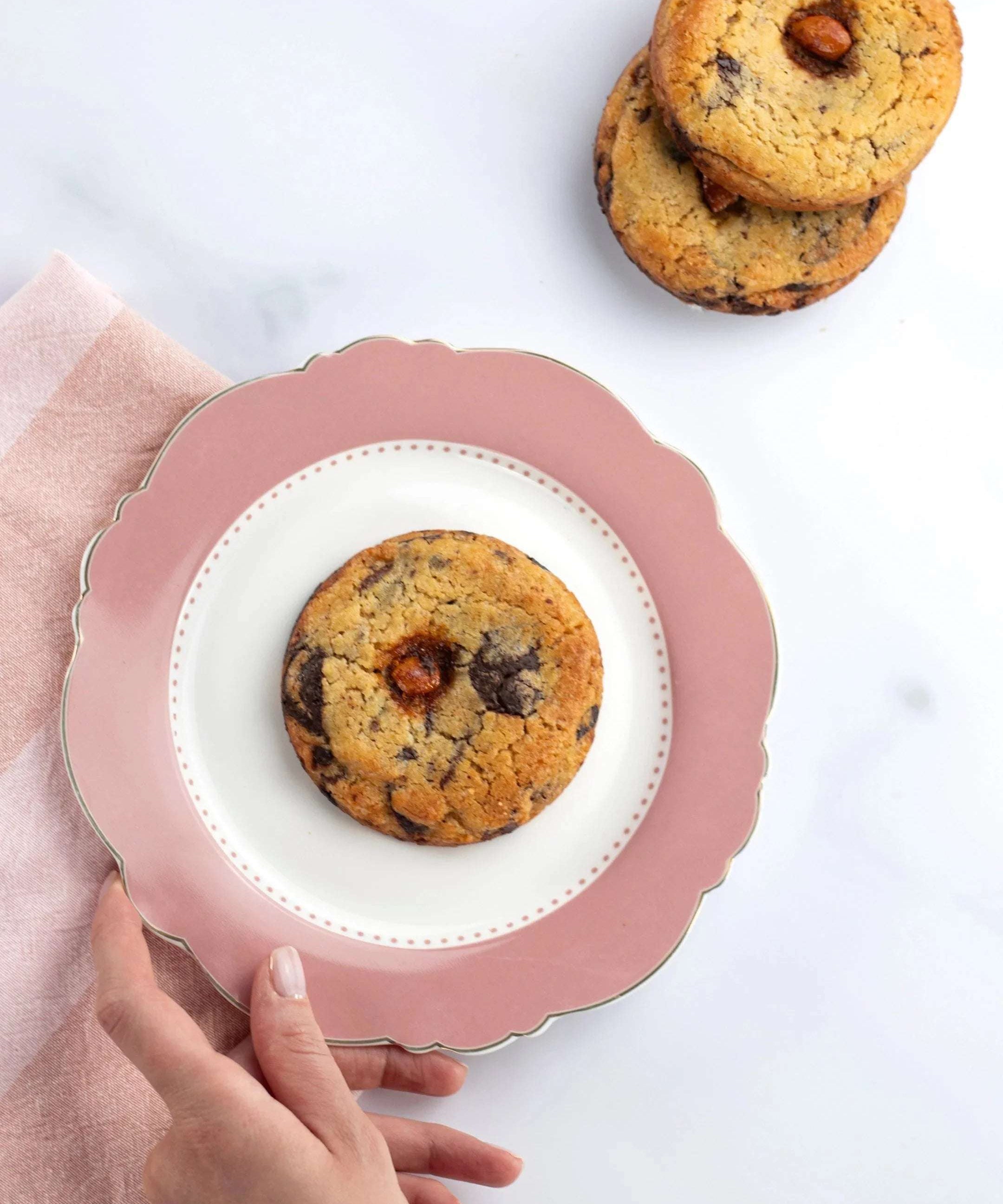 Cookie 3 Chocolats de Maison Vatelier sur une assiette rose avec des cookies en arrière-plan.
