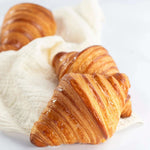 Trois croissants Maison Vatelier dorés et croustillants posés sur un linge blanc.