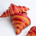 Gros plan de croissants à la framboise Maison Vatelier avec glaçage rouge brillant.