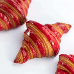 Gros plan de croissants Maison Vatelier nappés de glaçage framboise rouge brillant