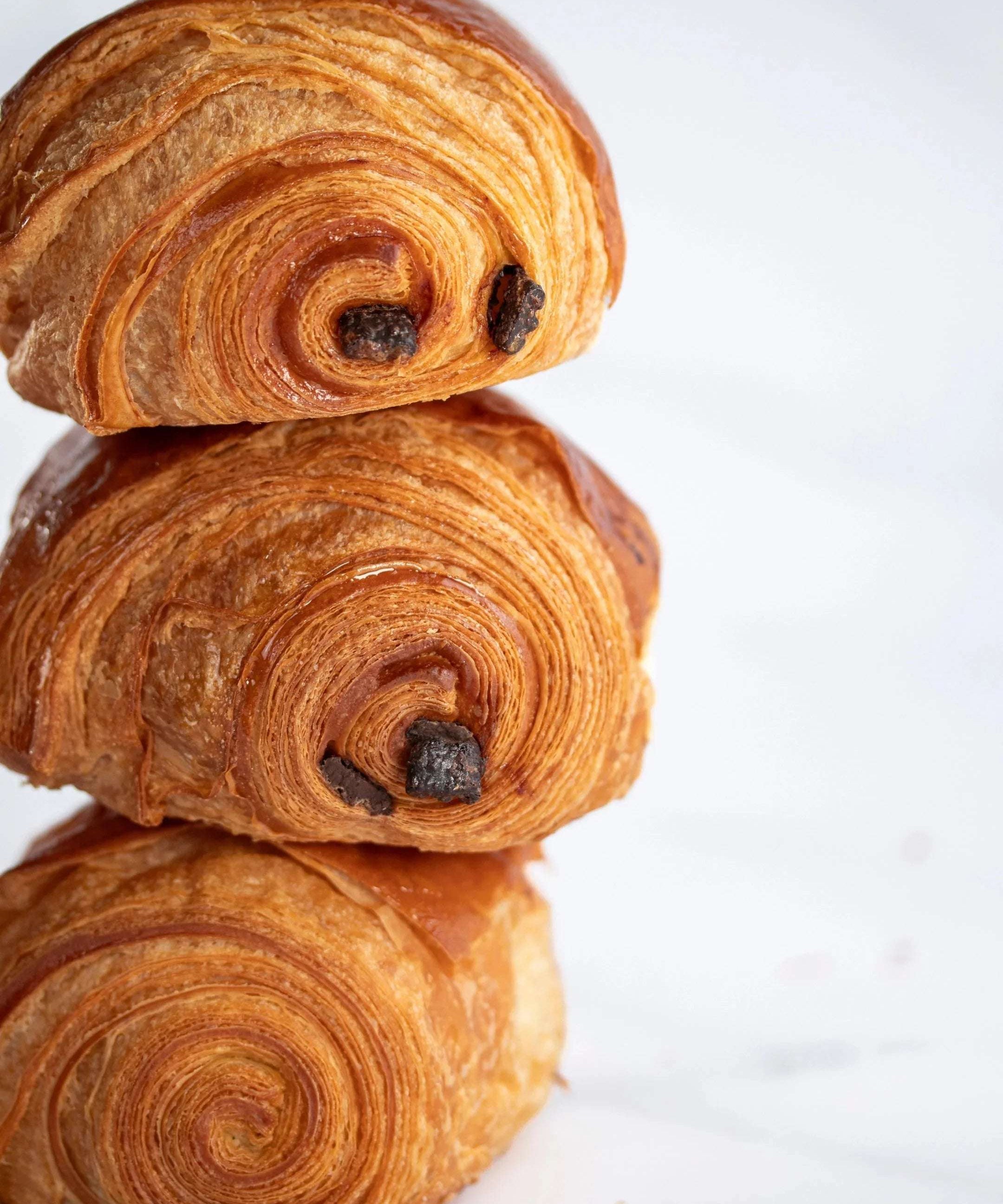 Pile de trois pains au chocolat feuilletés et dorés de Maison Vatelier.