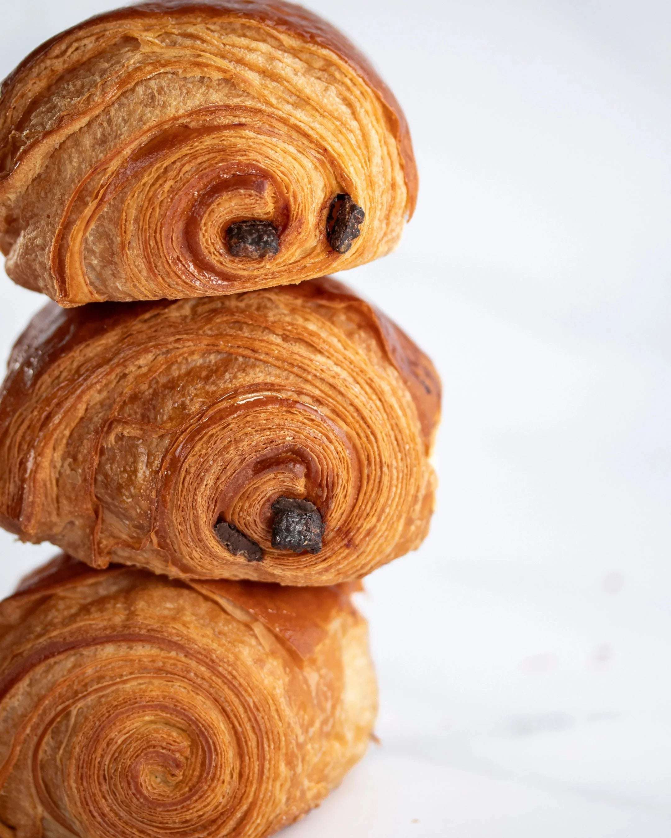Pile de trois pains au chocolat feuilletés et dorés de Maison Vatelier.