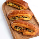 Trois viennoiseries feuilletées aux pépites de chocolat Maison Vatelier sur un plateau en bois.