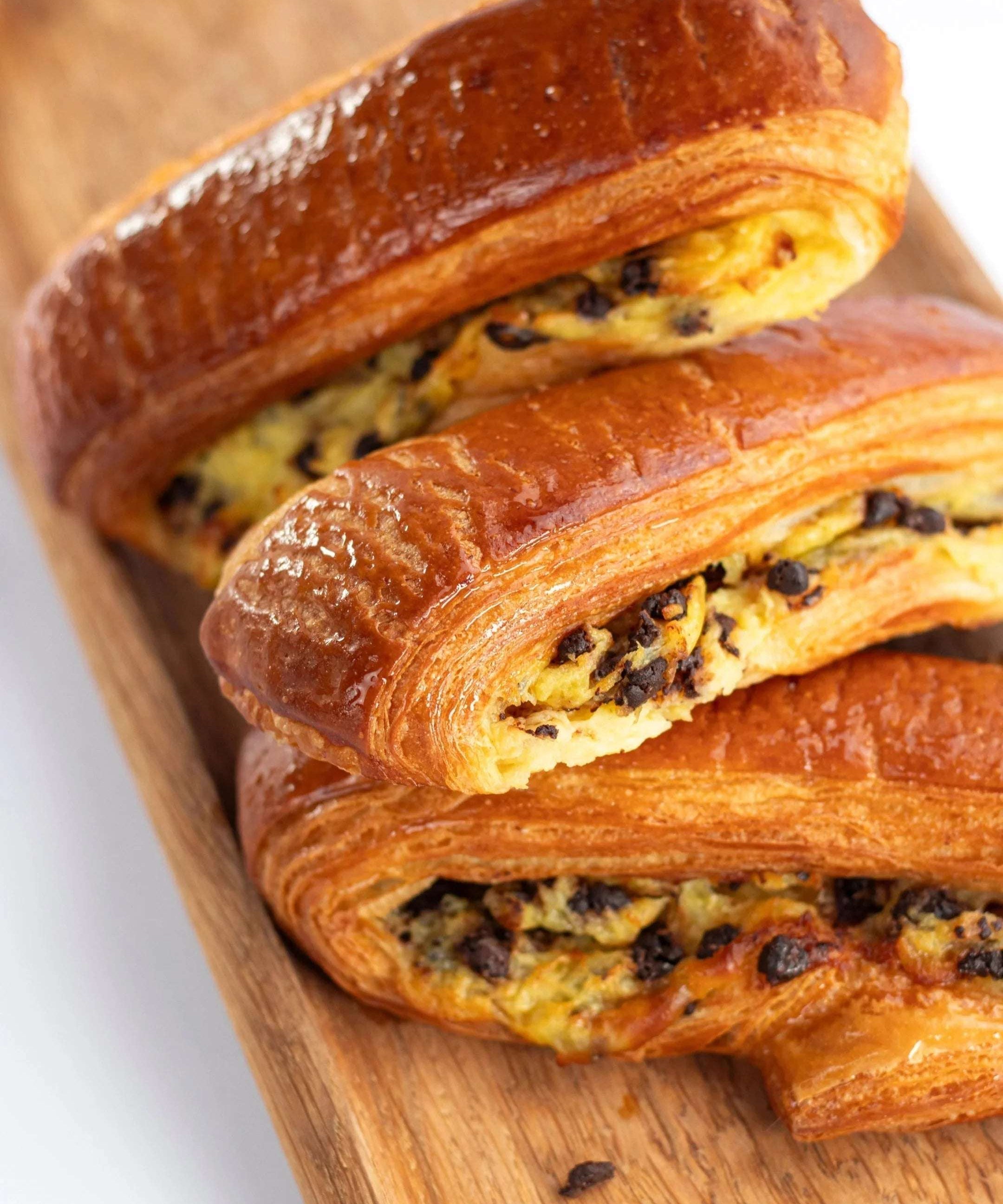 Viennoiseries feuilletées aux pépites de chocolat Maison Vatelier sur planche en bois.