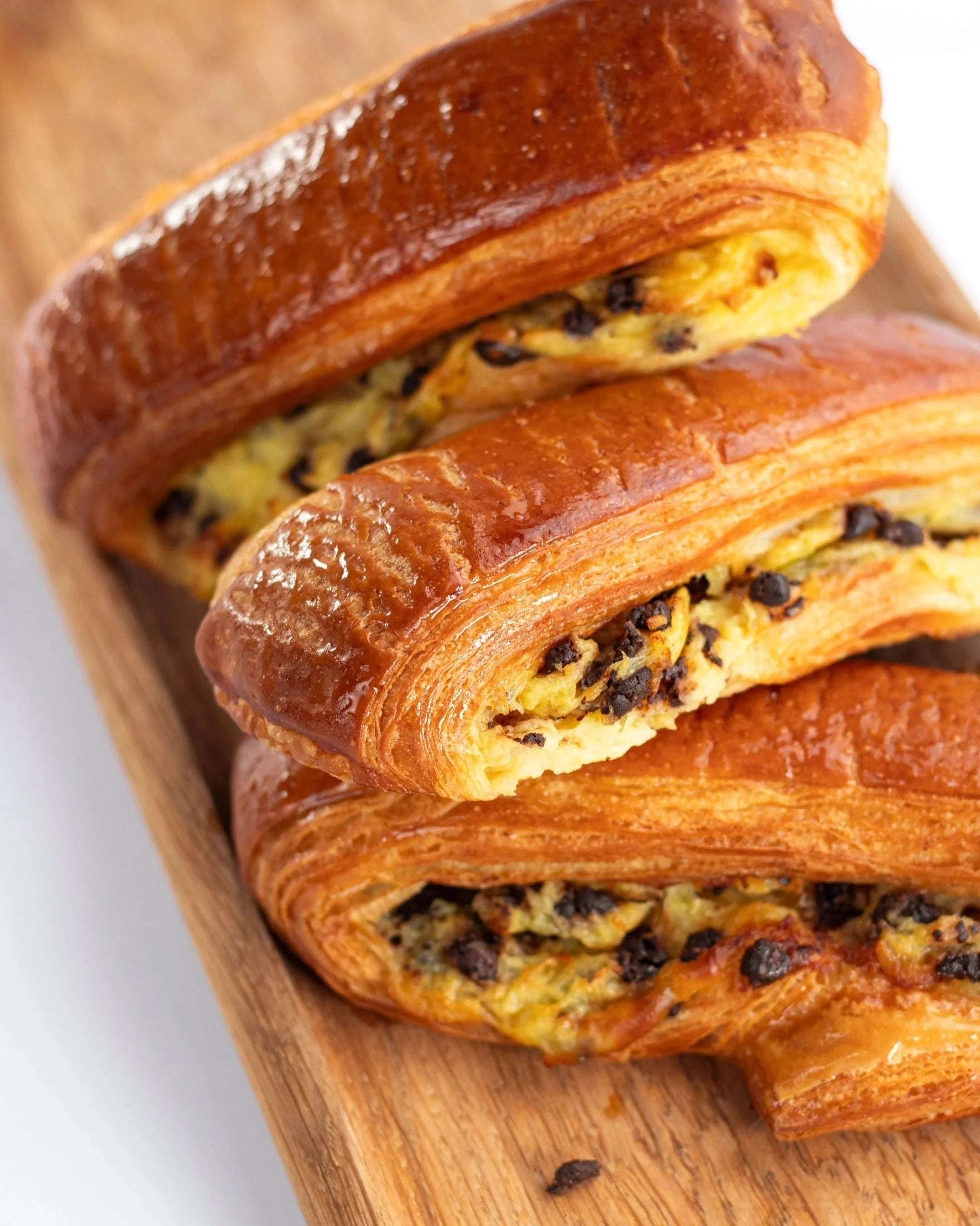 Viennoiseries feuilletées aux pépites de chocolat Maison Vatelier sur planche en bois.