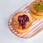 Financier à la framboise saupoudré de sucre glace de Maison Vatelier sur un plateau rayé.