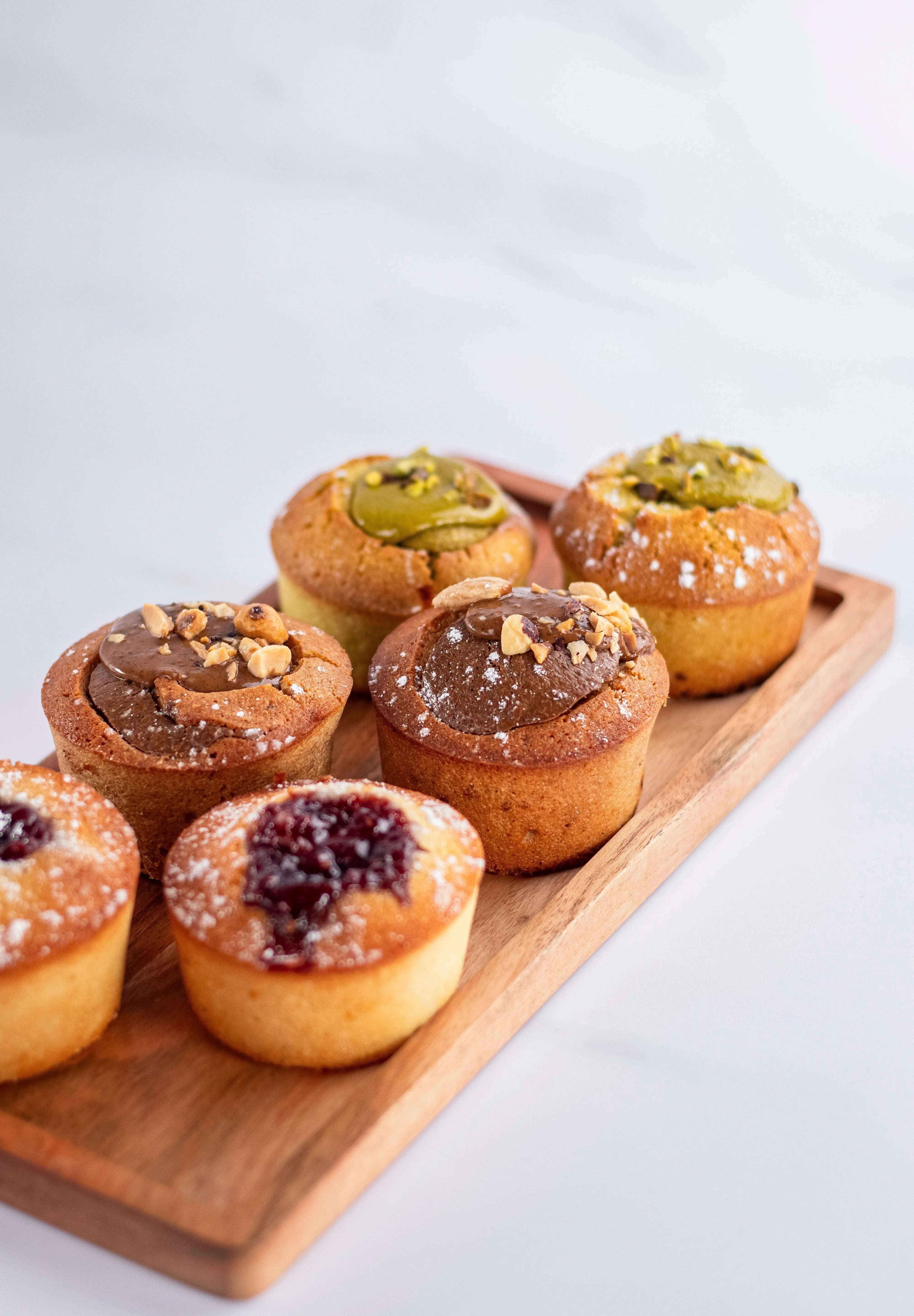 Assortiment de gâteaux de voyage Maison Vatelier, dont un financier framboise, sur plateau bois.