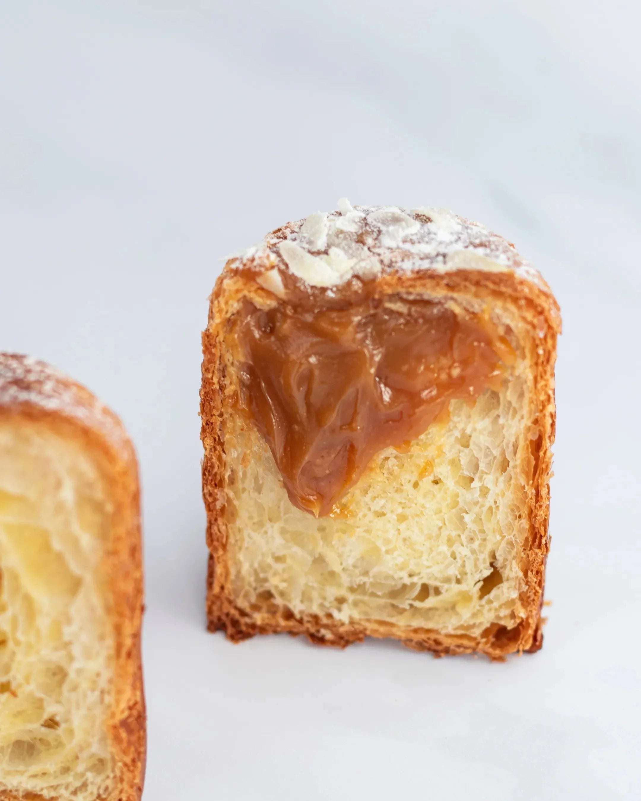 Vue en coupe d'une Briochette Feuilletée au caramel Maison Vatelier, saupoudrée de sucre glace.