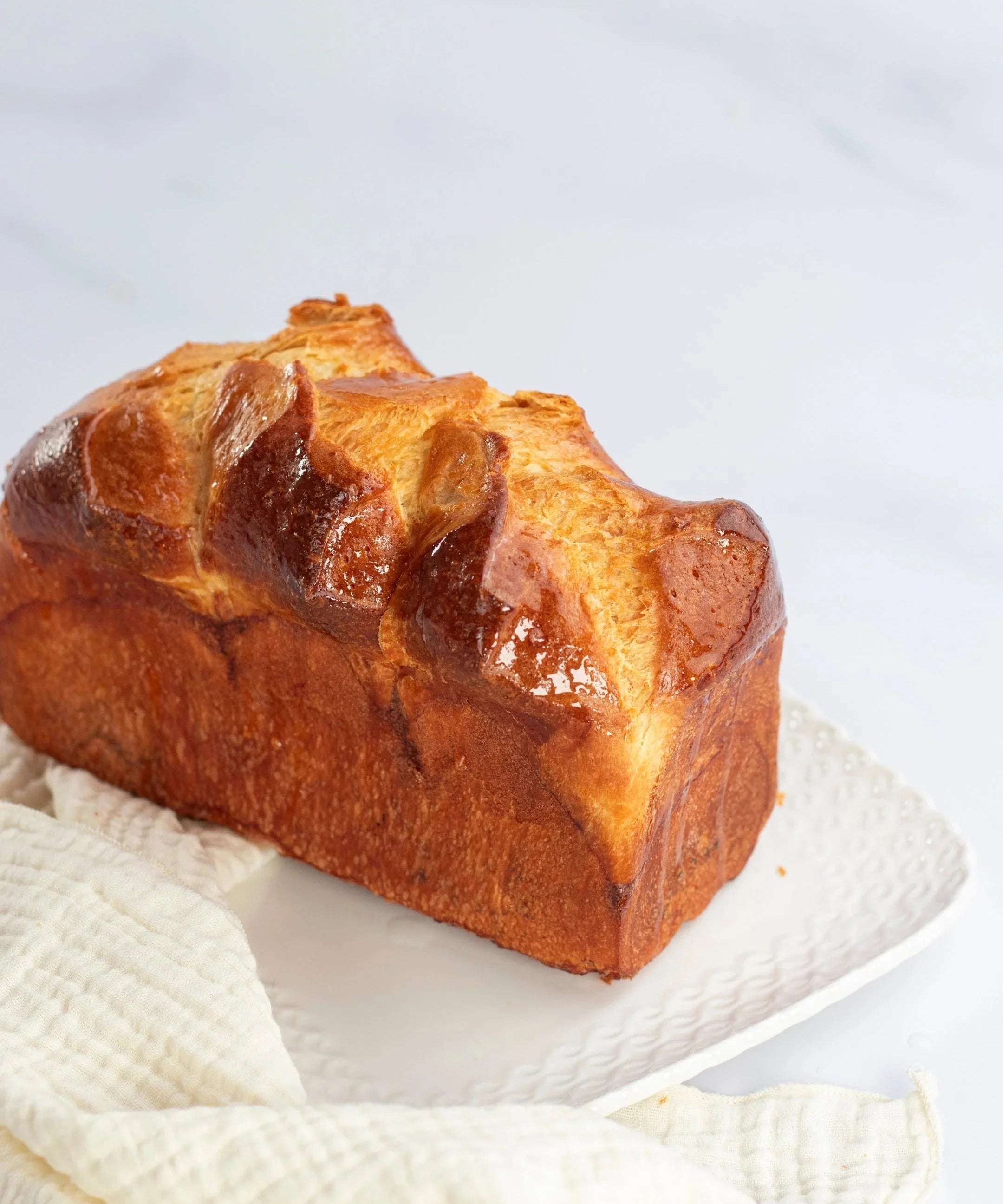 Brioche Longue Maison Vatelier dorée et moelleuse sur une assiette blanche