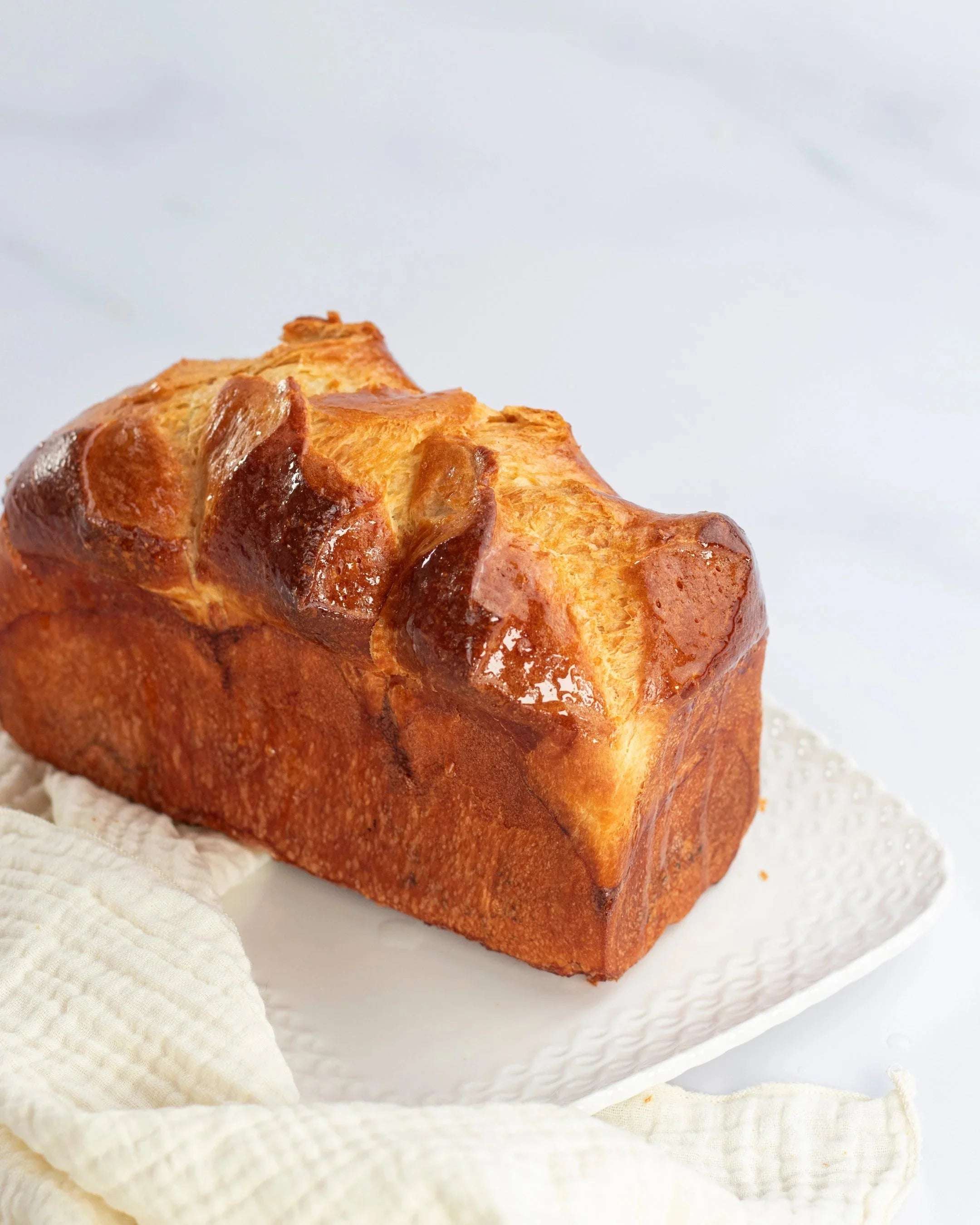 Brioche Longue Maison Vatelier dorée et moelleuse sur une assiette blanche