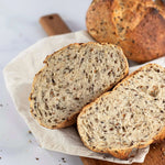 Tranches de pain aux 6 céréales Maison Vatelier sur une planche en bois.