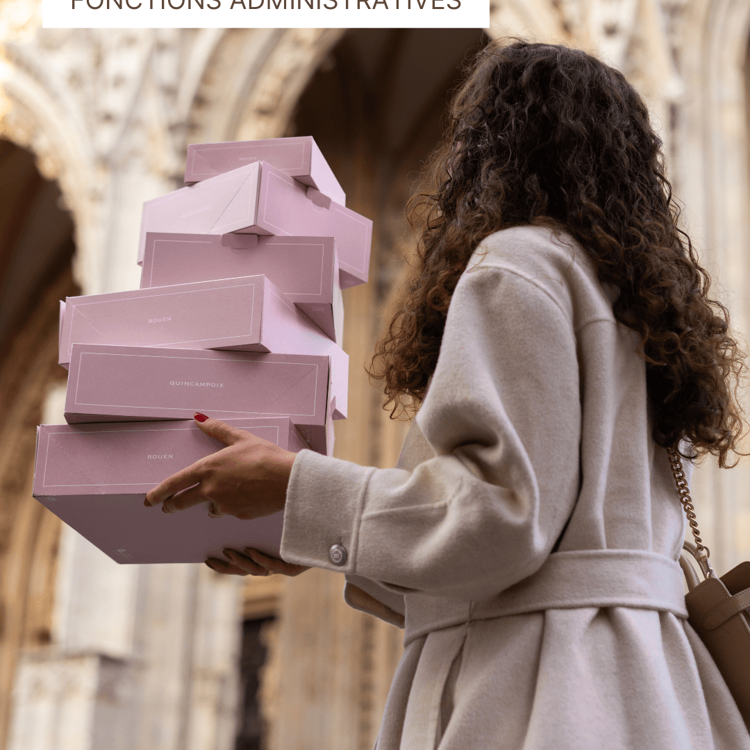 Femme portant une pile de boîtes à pâtisseries roses devant une architecture gothique.