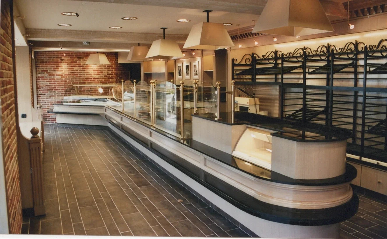 Intérieur d'une pâtisserie avec comptoirs vitrés et étagères à pain.