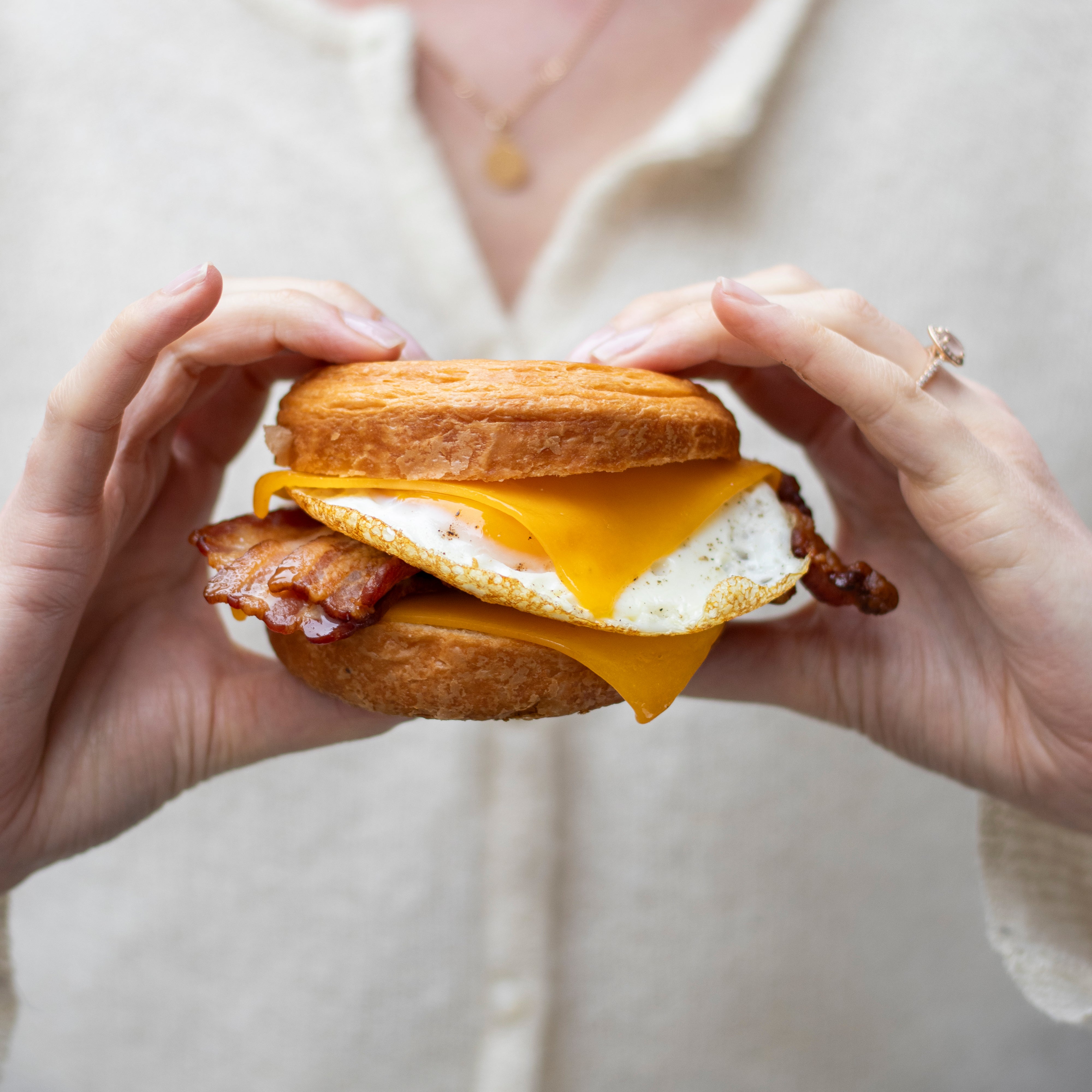 Gros plan d'un sandwich petit-déjeuner avec œuf, bacon et fromage fondant dans un bun doré.