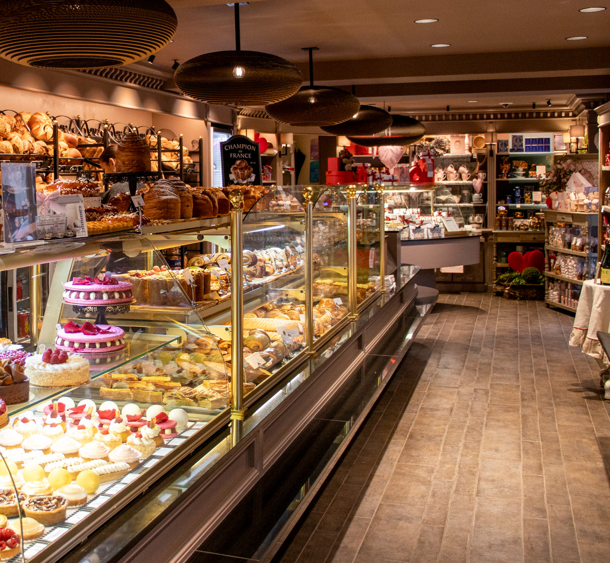 Intérieur d'une boulangerie-pâtisserie avec vitrine de gâteaux et étagères de pains artisanaux.