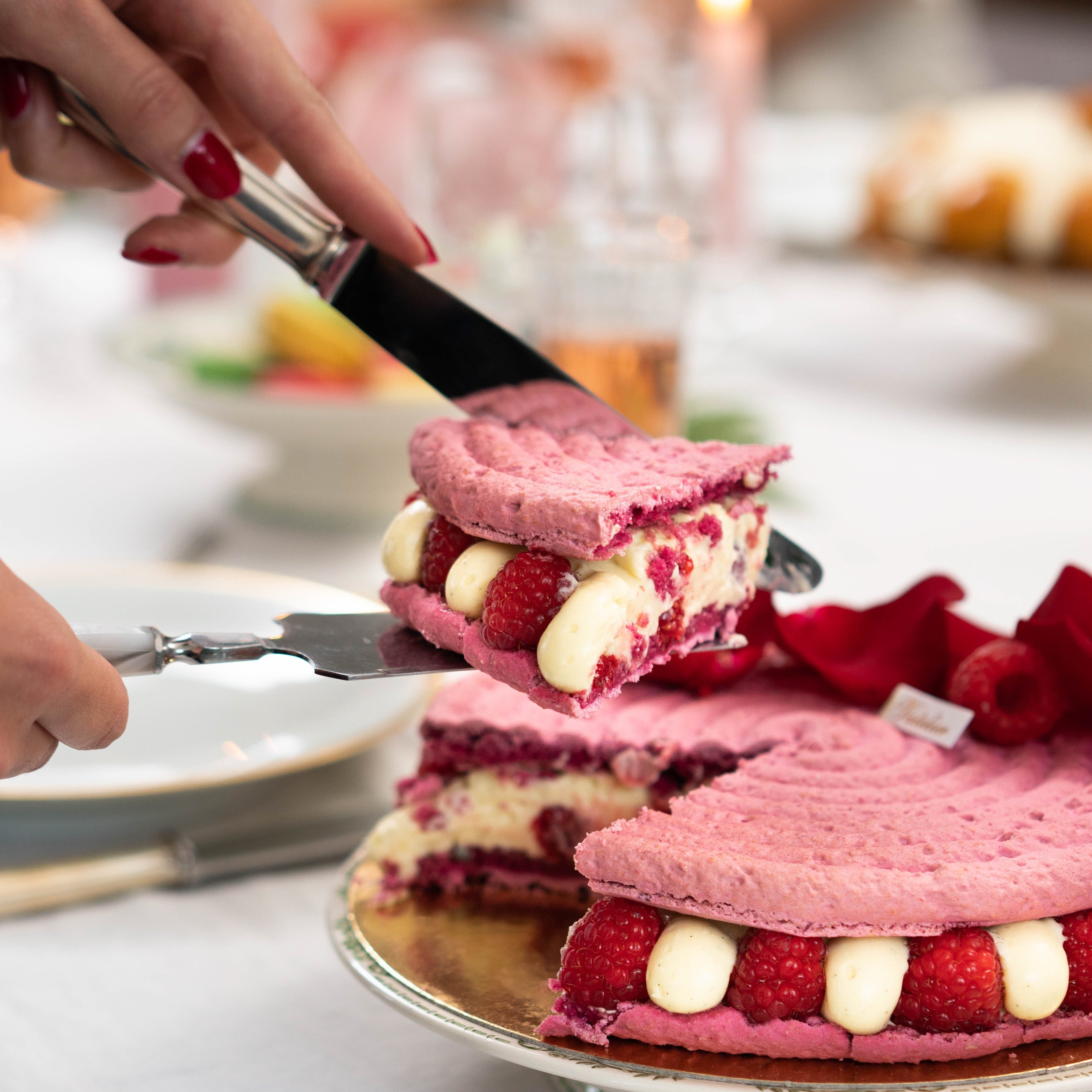 Part de gâteau à la framboise et crème sur un plat, servie avec une spatule.
