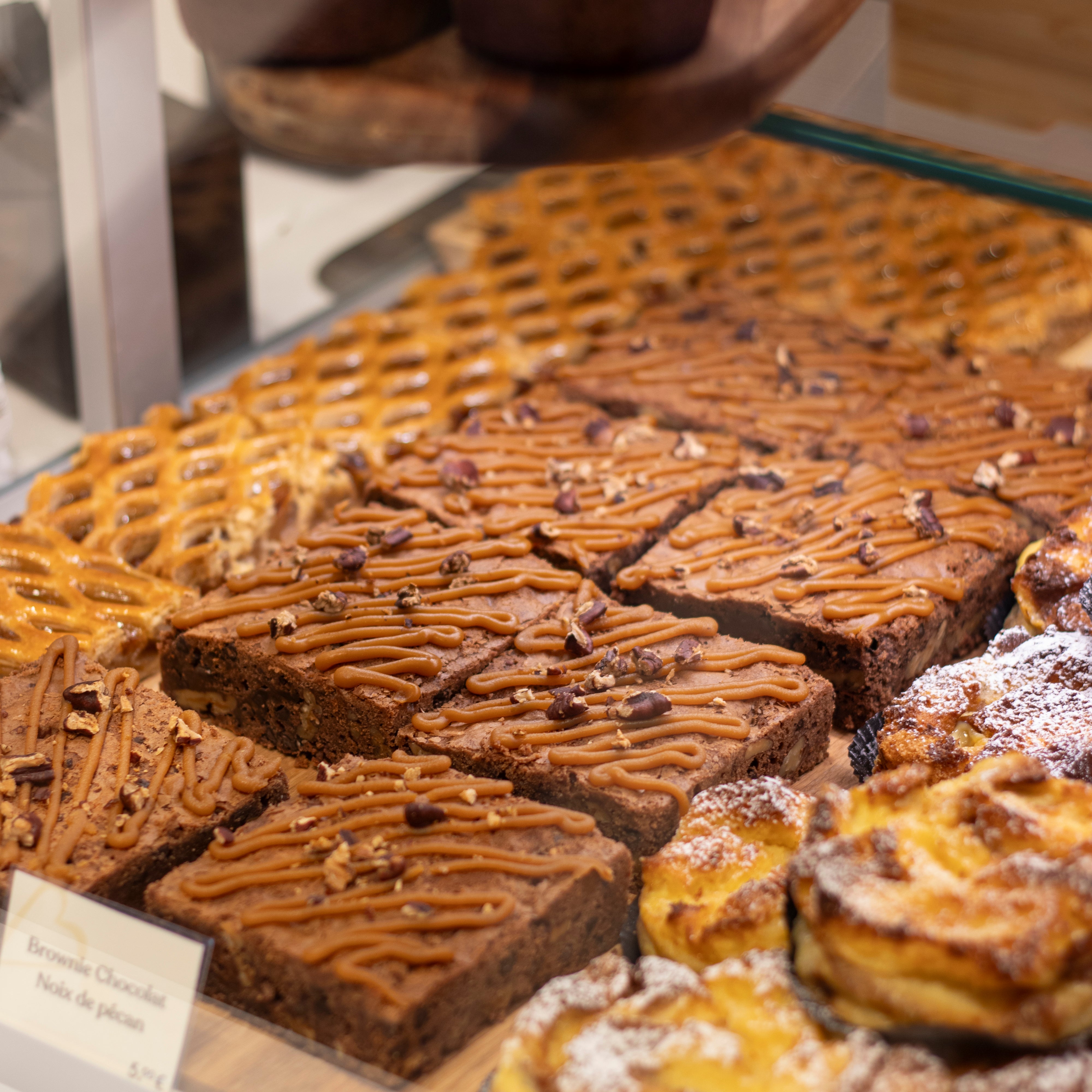 Assortiment de brownies au chocolat et pâtisseries artisanales en vitrine.