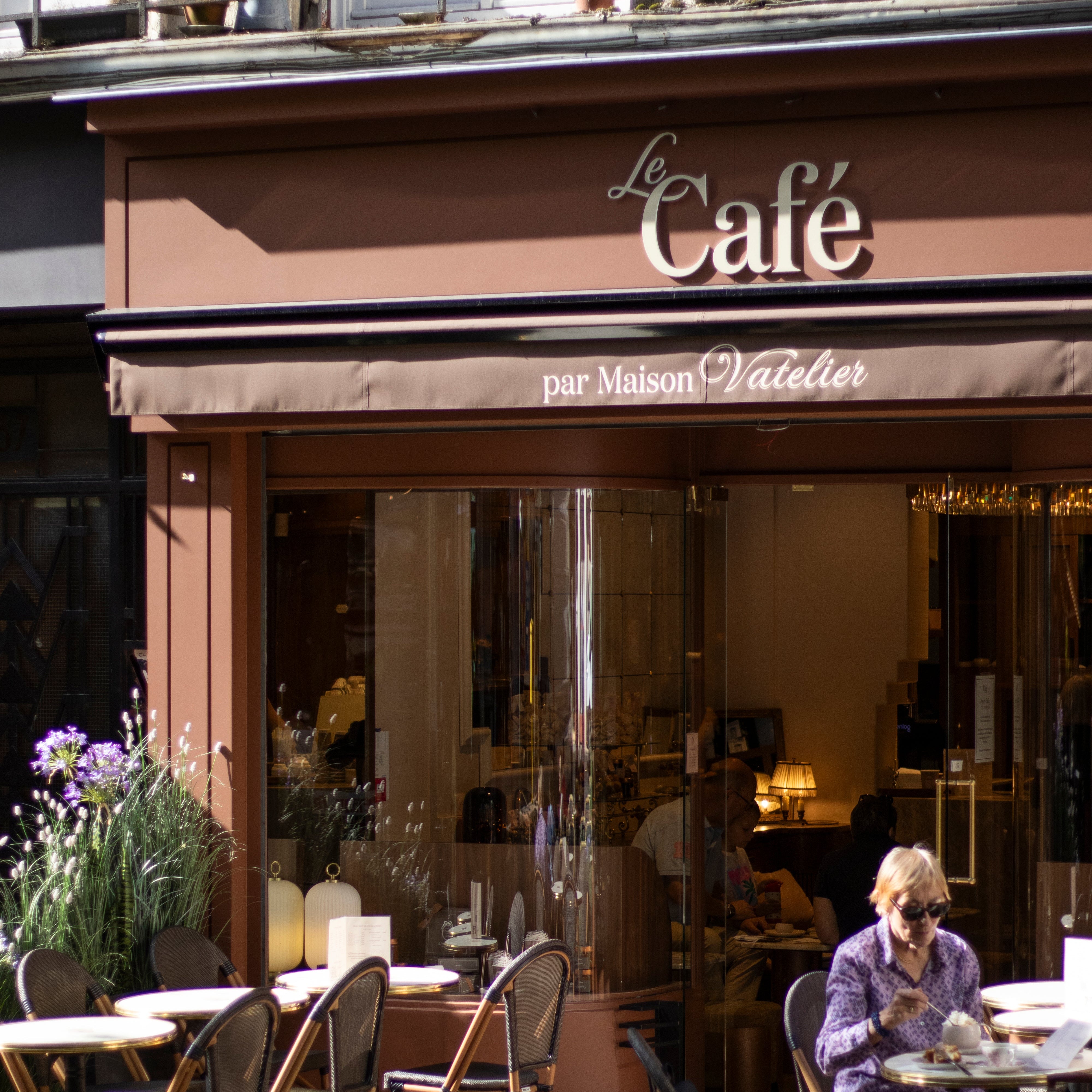 Façade du Le Café par Maison Vatelier avec terrasse et clients à l'intérieur.
