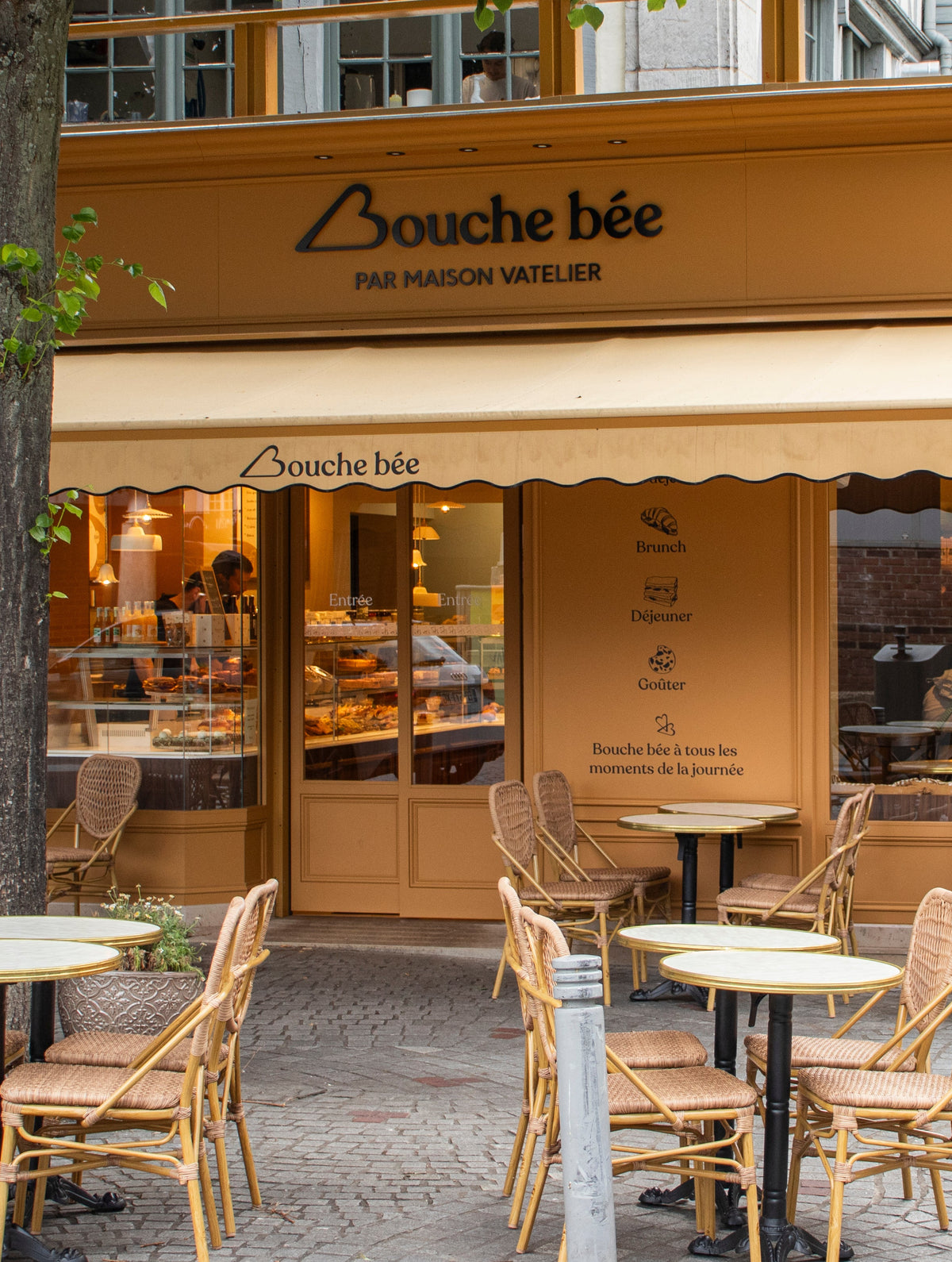 Façade de la pâtisserie-boulangerie Bouche bée avec terrasse et tables rondes.