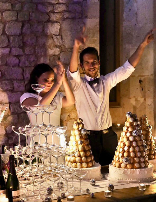 Couple célébrant avec une pyramide de choux et une tour de coupes de champagne.