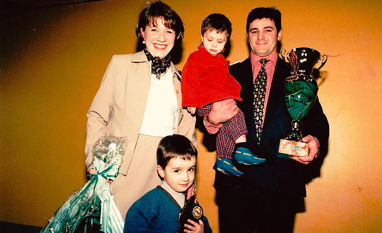 Photo de famille vintage avec un homme tenant un trophée, une femme et deux enfants.
