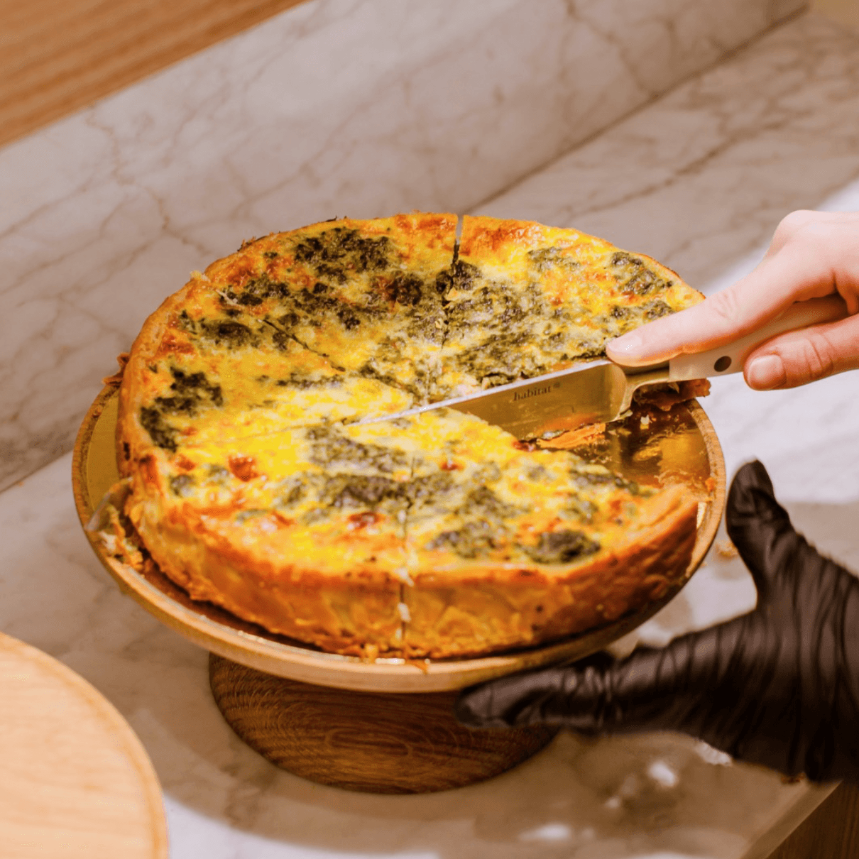 Une quiche aux épinards et fromage coupée en parts sur un présentoir.