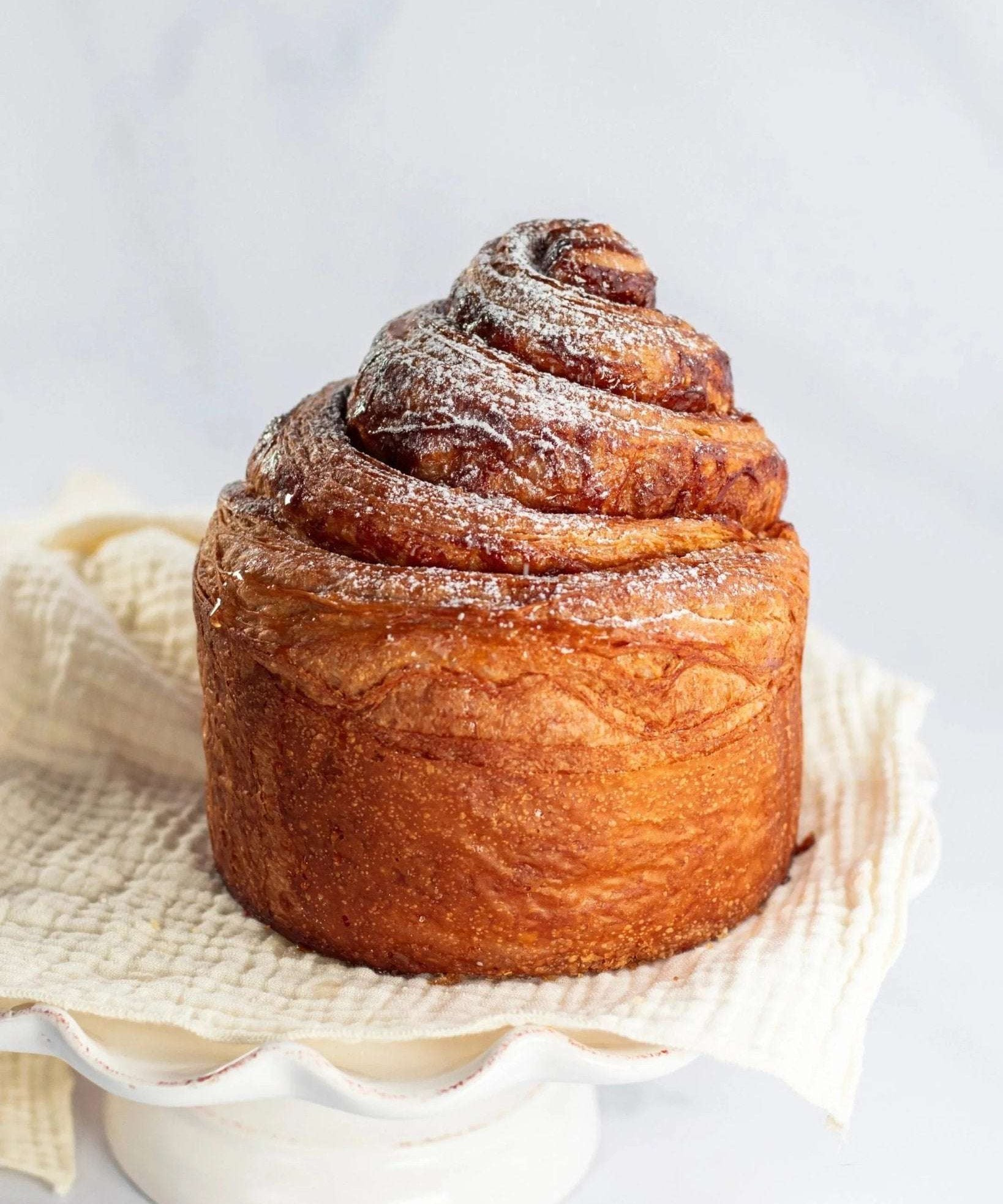 Brioche feuilletée Maison Vatelier saupoudrée de sucre glace sur un support blanc.