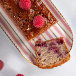 Cake framboise noisette Maison Vatelier avec framboises fraîches sur un plat rayé.