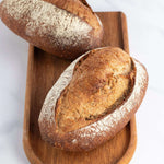Deux pains de campagne artisanaux croustillants sur une planche en bois Maison Vatelier.