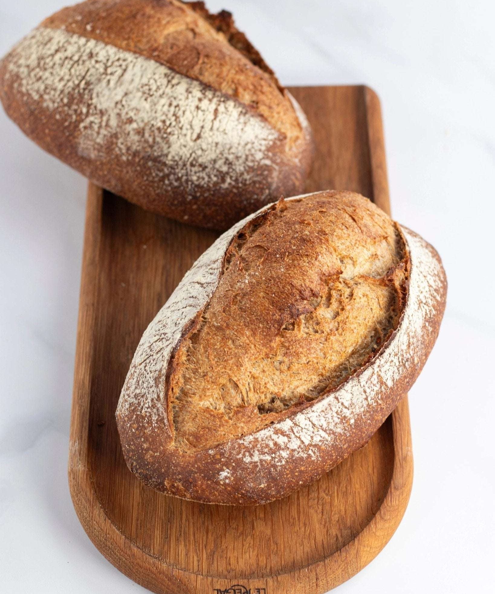 Deux pains de campagne artisanaux croustillants sur une planche en bois Maison Vatelier.
