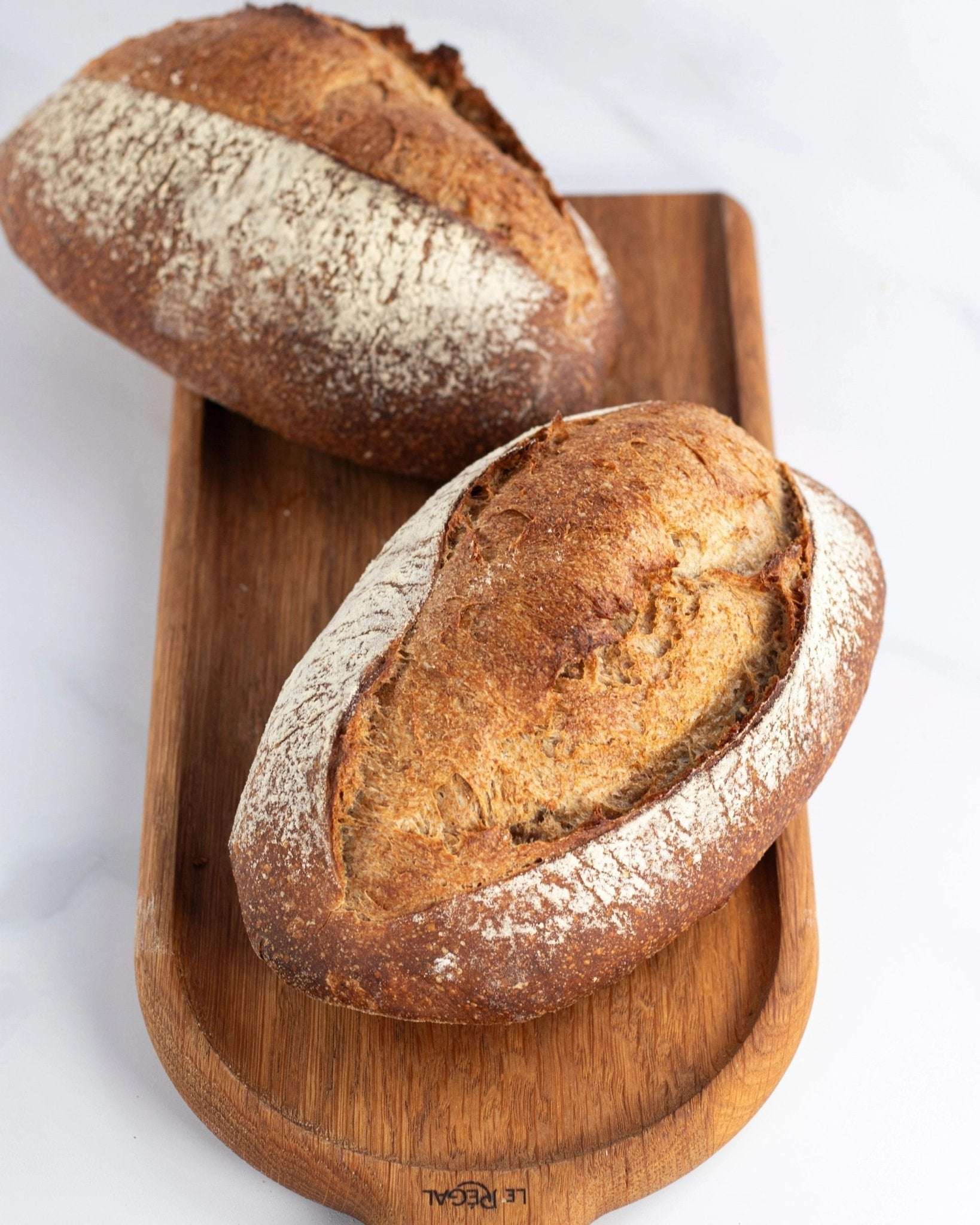 Deux pains de campagne artisanaux croustillants sur une planche en bois Maison Vatelier.