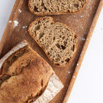 Tranches de pain de campagne artisanal sur une planche en bois avec farine.