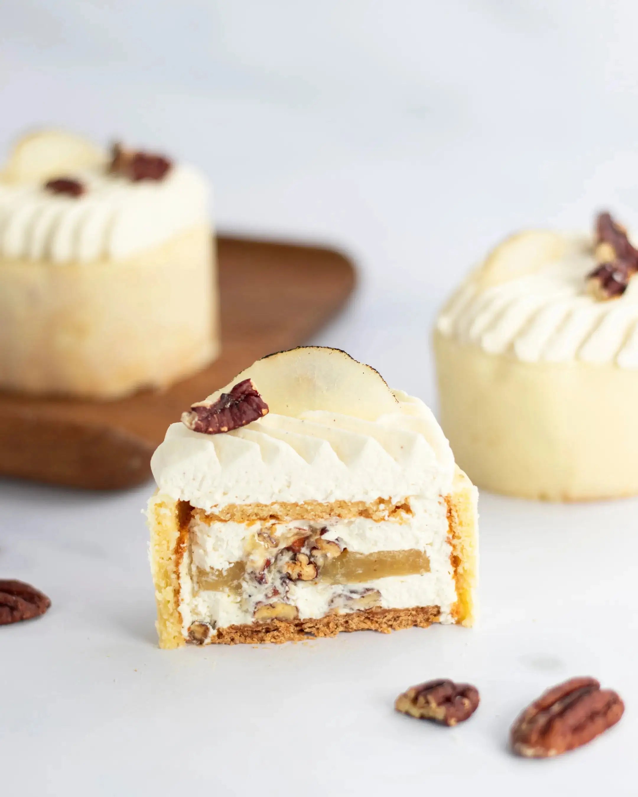 Gros plan d'une part de gâteau à la crème et noix avec une tranche de poire.