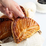 Main prenant un chausson aux pommes doré et croustillant de Maison Vatelier.