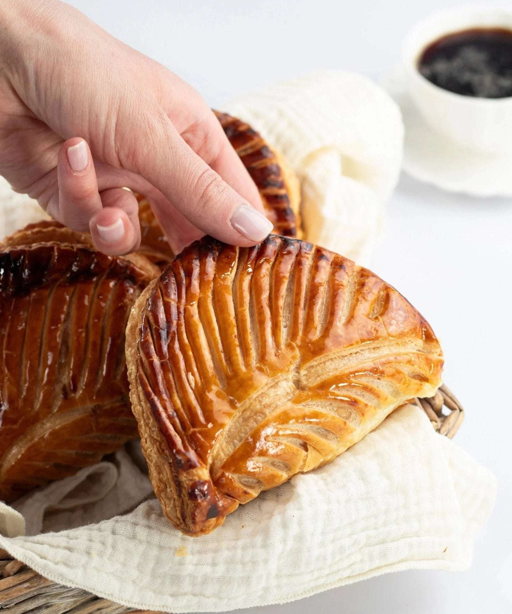 Main prenant un chausson aux pommes doré et croustillant de Maison Vatelier.
