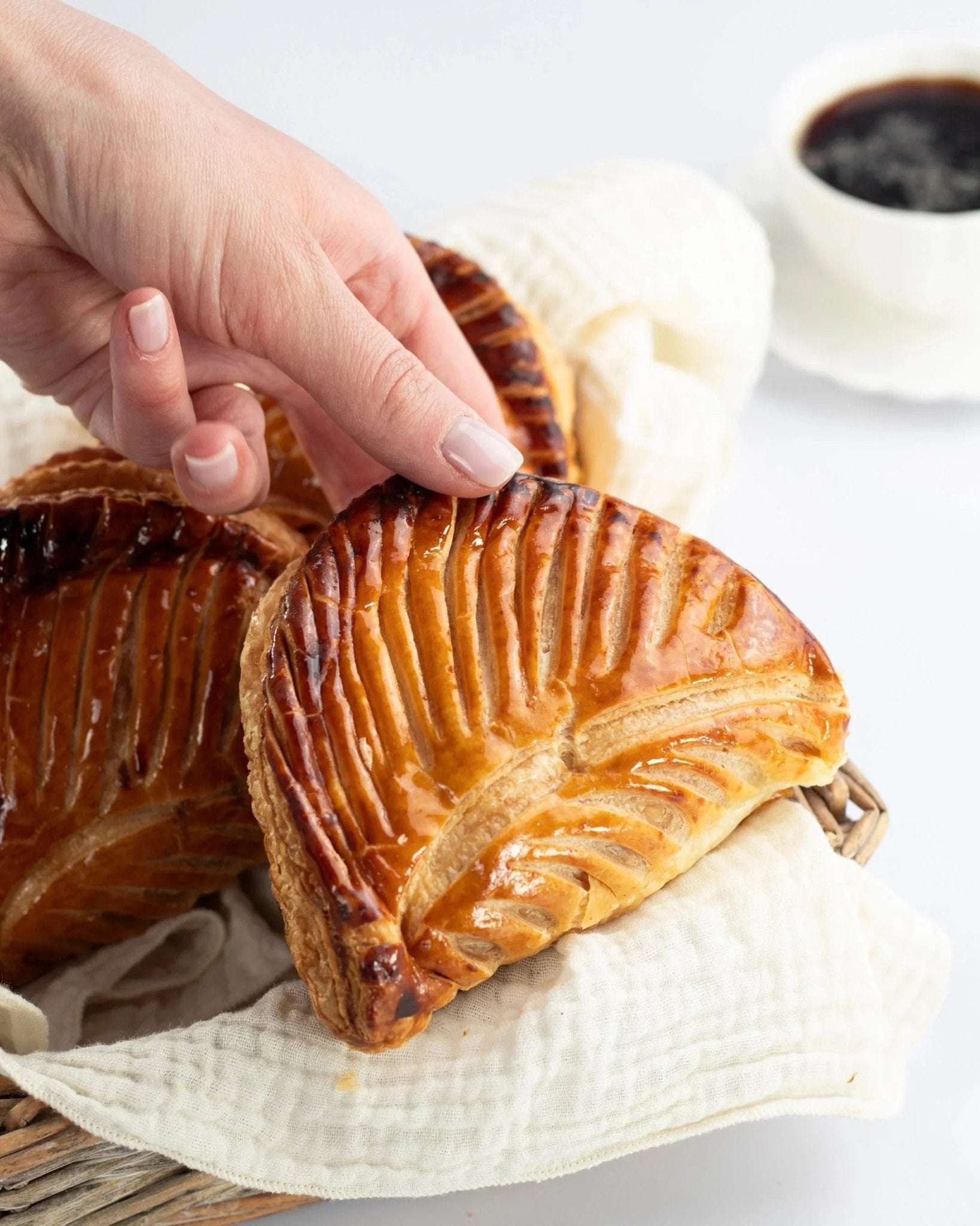 Main prenant un chausson aux pommes doré et croustillant de Maison Vatelier.