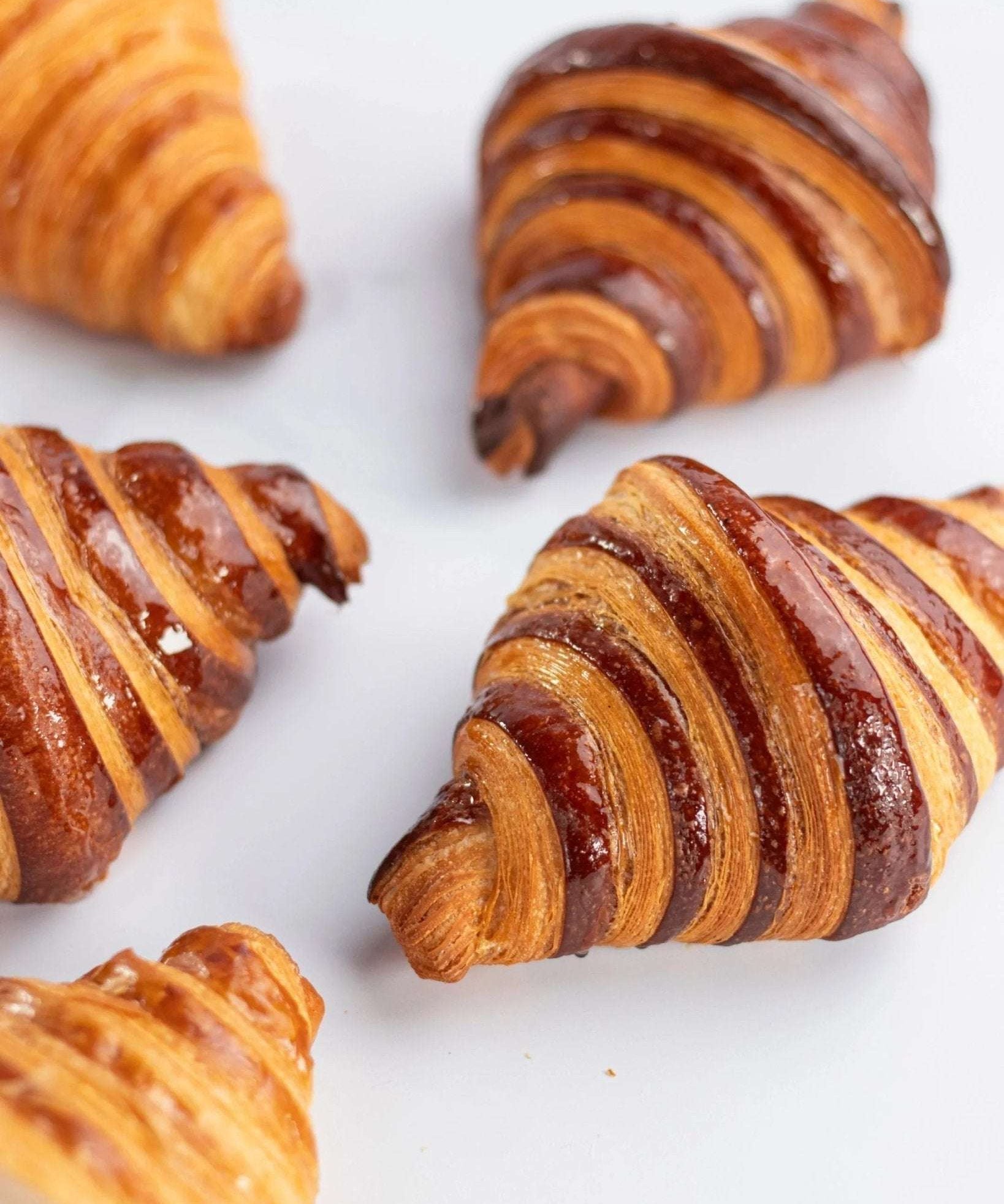 Gros plan de croissants au chocolat Maison Vatelier, dorés et glacés.